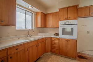 Kitchen featuring light countertops, a sink, oven, and brown cabinets