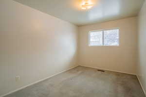 Spare room featuring light carpet, visible vents, and baseboards