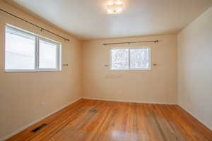 Spare room with light wood finished floors, visible vents, and baseboards