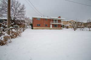 Snow covered rear of property with a balcony