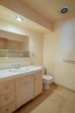 Bathroom featuring toilet, visible vents, and vanity