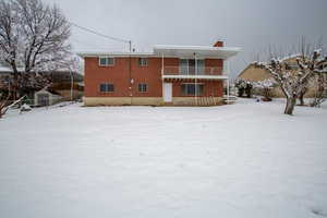 Snow covered house featuring a balcony and a chimney