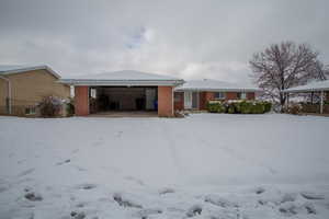 Snow covered property featuring brick siding