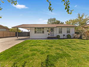 Ranch-style home with fence, a front lawn, a carport, and brick siding