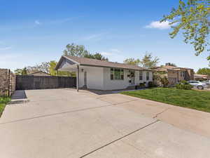 Ranch-style home with concrete driveway, an attached carport, fence, a front lawn, and brick siding