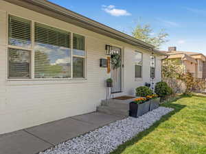 Property entrance with a yard and brick siding