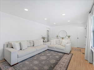 Living area with recessed lighting, visible vents, light wood-type flooring, and baseboards