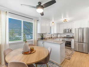 Kitchen with light wood-style flooring, a peninsula, white cabinetry, a sink, and stainless steel appliances