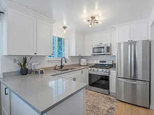 Kitchen with a sink, white cabinets, and appliances with stainless steel finishes