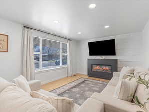 Living room featuring wood finished floors, baseboards, a large fireplace, and recessed lighting