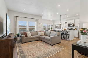 Living room with a chandelier, a textured ceiling, recessed lighting, and light wood-style floors