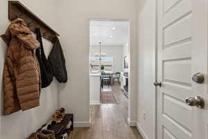 Mudroom featuring baseboards, a textured ceiling, wood finished floors, and a notable chandelier