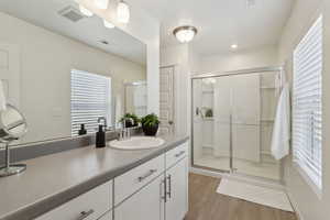 Bathroom with visible vents, vanity, a shower stall, and wood finished floors