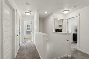 Corridor with carpet flooring, visible vents, an upstairs landing, baseboards, and washer and clothes dryer