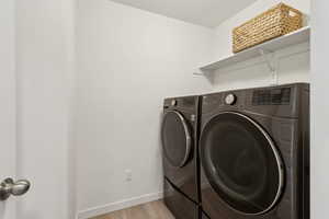 Washroom featuring baseboards, laundry area, light wood-style floors, and washer and dryer