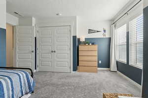 Bedroom featuring light carpet, a closet, a textured ceiling, and visible vents