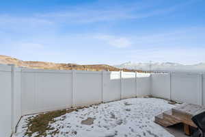 Yard covered in snow with a fenced backyard and a mountain view