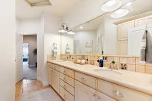 Bathroom with double vanity, tile patterned flooring, a sink, and decorative backsplash