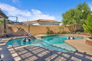 View of pool with a pool with connected hot tub and a fenced backyard