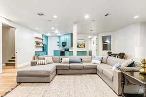 Living area featuring light wood-style floors, recessed lighting, visible vents, and stairs