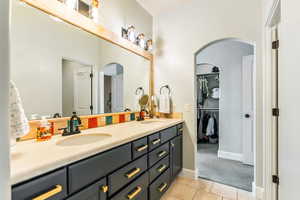 Bathroom featuring double vanity, a walk in closet, a sink, and tile patterned floors