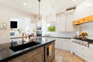 Kitchen featuring premium range hood, a sink, white cabinets, appliances with stainless steel finishes, and dark countertops