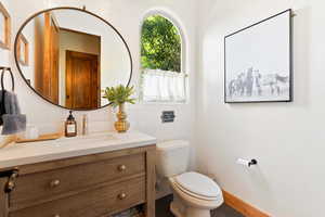 Half bath with tile walls, tasteful backsplash, toilet, vanity, and baseboards