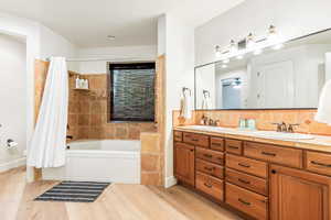 Full bath with backsplash, a sink, and wood finished floors