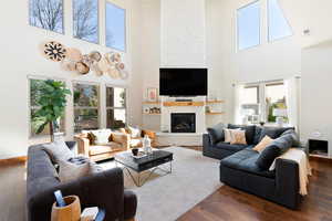 Living room featuring dark wood-style flooring, a fireplace, visible vents, and baseboards