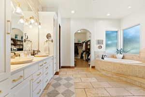 Bathroom with a spacious closet, a sink, stone tile flooring, and recessed lighting