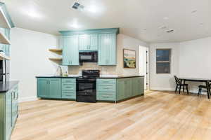 Kitchen featuring green cabinets, visible vents, black appliances, and open shelves