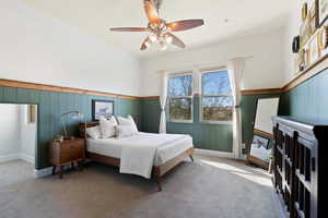 Bedroom with a wainscoted wall, carpet, and ceiling fan