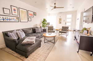 Living area with light tile patterned floors, a ceiling fan, and an AC wall unit