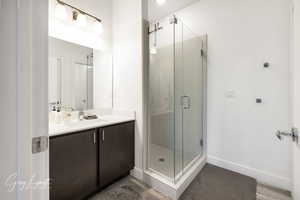 Bathroom featuring a shower stall, vanity, and baseboards