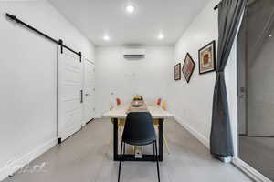 Dining space with light tile patterned floors, a barn door, baseboards, a wall mounted air conditioner, and recessed lighting