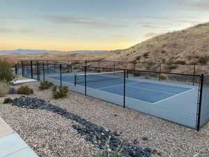 View of tennis court featuring a mountain view and fence