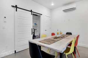 Dining room featuring an AC wall unit, light tile patterned floors, baseboards, and a barn door