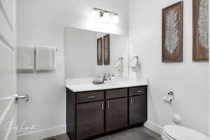 Bathroom with toilet, vanity, and baseboards