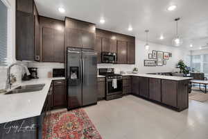 Kitchen featuring stainless steel appliances, light countertops, a sink, and dark brown cabinetry