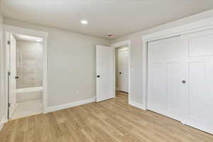 Unfurnished bedroom with light wood-type flooring, a closet, baseboards, and connected bathroom