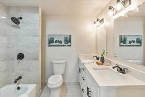 Bathroom with double vanity, a sink, toilet, and baseboards