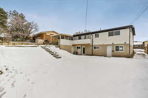 Snow covered property featuring central AC, brick siding, and fence