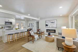 Living area featuring light wood-style floors, recessed lighting, french doors, and a glass covered fireplace