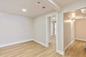 Unfurnished room with recessed lighting, visible vents, light wood-style flooring, and baseboards