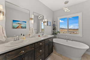 Full bathroom featuring a sink, tile patterned flooring, double vanity, and a freestanding bath