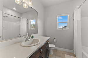 Full bathroom featuring toilet, shower / tub combo, vanity, tile patterned flooring, and baseboards