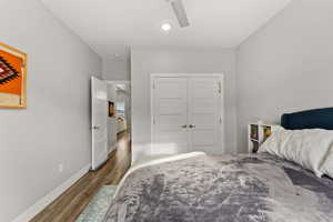 Bedroom with dark wood-style floors, ceiling fan, baseboards, and a closet