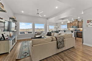 Living room with ceiling fan with notable chandelier, baseboards, wood finished floors, and recessed lighting