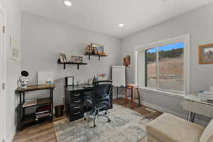 Office area with dark wood-style floors, recessed lighting, visible vents, and baseboards