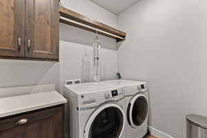 Washroom with cabinet space, baseboards, and washer and clothes dryer